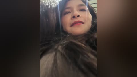 Video of a person wearing a furry animal costume, possibly a bear, with a neutral expression and red lipstick, in a dimly lit room with blurred background.