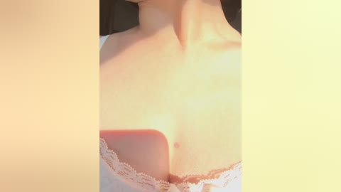 Close-up video of a fair-skinned woman's chest in a white lace bra, showcasing smooth skin and a hint of cleavage. The background is a warm, soft-toned gradient.