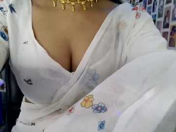 Media: A close-up video of a woman in a white blouse with floral embroidery, revealing cleavage, wearing a gold necklace. Background features a colorful collage of photos.