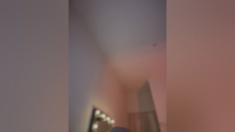 A blurry, dimly lit video of an indoor scene with a large, partially obscured figure in the center, likely male, standing in front of a mirror with bright, circular lights reflecting off it.