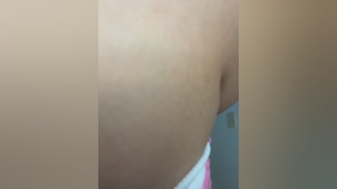 A close-up video of a woman's bare buttocks, featuring light brown skin and a slight crease, with a blurred background suggesting a bathroom setting.