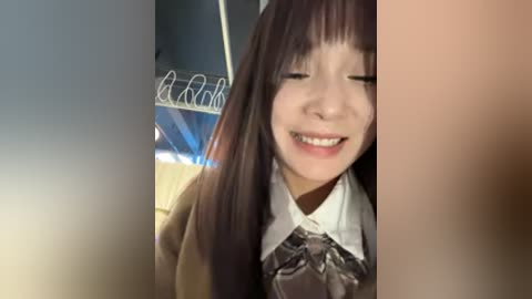 Video of a young Asian woman with straight, dark hair, wearing a school uniform with a white blouse and gray tie, smiling with closed eyes.