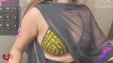 Video of a woman in a black, semi-transparent saree with a leopard-print bra. The background shows a calendar with dates and a pink heart.