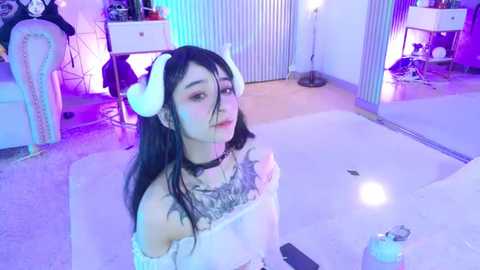 Video of a young Asian woman in a white off-shoulder dress, wearing white cat ears and a choker, standing in a modern, softly lit bathroom with a white bathtub, blue-tinted lights, and a mirror.