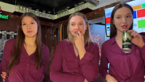Video of three young women, all with straight brown hair, wearing maroon shirts, standing in a bar. One drinks beer, one eats a cookie, and one looks at camera.