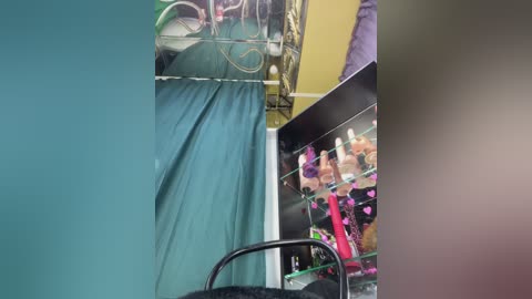 Video of a hospital room with a teal curtain, a person in a green gown, medical equipment, and a colorful toy display on a shelf.