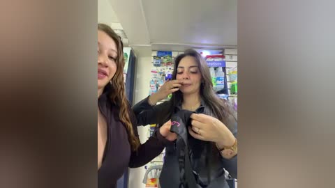 Video of a woman with long brown hair, wearing a black top, adjusting a black scarf in a convenience store.