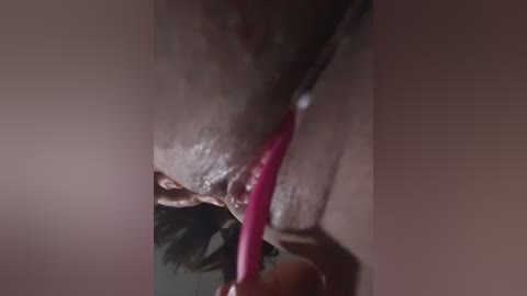 A close-up video of a woman's nipple, with a pink vibrator inserted, showing wetness and arousal. Her skin tone is light brown, and her dark hair is visible at the top.