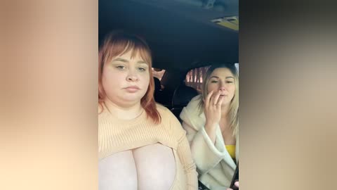 Video of two women in a car, one with red hair and pale skin, the other with blonde hair and pale skin, both wearing light-colored sweaters.