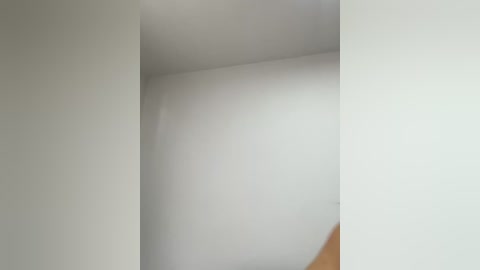 Video of a white, smooth, seamless corner in a minimalist interior space, featuring a subtle, natural light reflection on the wall, highlighting the clean, unadorned aesthetic.