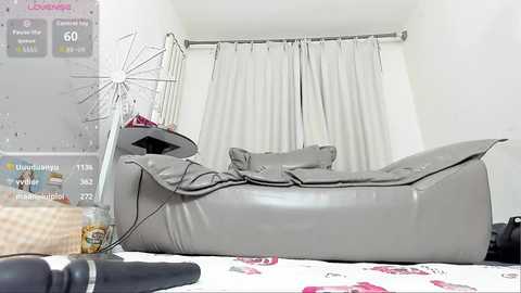 Video of a grey leather recliner chair with a black handle, positioned in a minimalist, white-walled room with a white curtain backdrop.