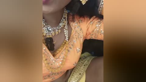 Video of a dark-skinned woman wearing a vibrant orange, gold-sequined saree adorned with intricate embroidery. She has a heavy silver necklace and matching earrings, and a golden belt with intricate patterns.