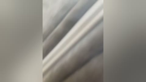 This is a close-up video of a smooth, textured surface with a glossy finish, featuring soft, parallel waves in shades of gray and white, creating a sense of depth and movement.