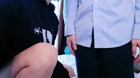Video of a pregnant woman in a black shirt with a white symbol, standing next to a man in a light blue shirt and dark pants.
