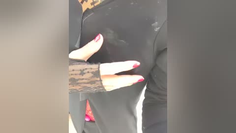 A video of a woman's hands in black lace gloves, with red nails, gripping the back of a black leather jacket, emphasizing a sensual, provocative touch. The background is blurred.