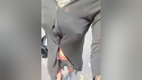 Video of a person in a dark suit, with a red and yellow patterned shirt visible through the jacket, walking in a blurred urban setting, capturing a sense of movement and urban energy.