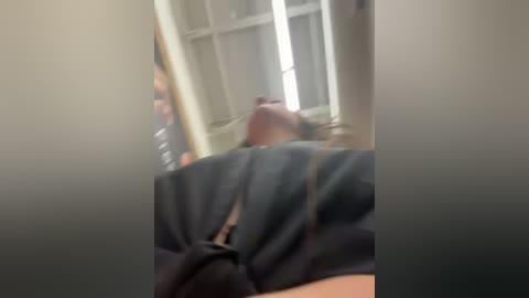 Video of a person lying on a bed, wearing a dark shirt, with a blurred face, and a window in the background. The room is dimly lit.