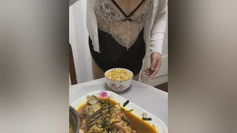 Video of a woman in a white lace top, black lingerie, and robe feeding a bowl of yellow curry to another person in a dimly lit room.