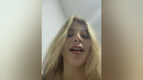 A video of a young Caucasian woman with straight, blonde hair and light skin, looking upwards with her mouth open, set against a white background.