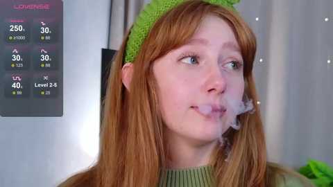 Video of a pale-skinned, red-haired woman with freckles, wearing a green knit cap, exhaling smoke. Background shows a digital screen with temperature, humidity, and pressure readings.