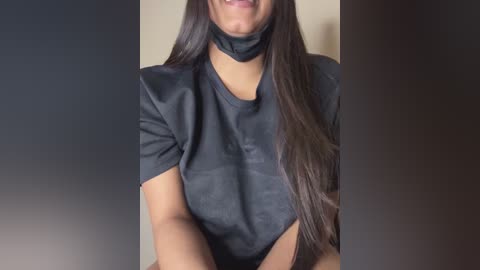 Video of a woman with medium skin tone, wearing a black leather choker and short-sleeved leather dress. Her long, straight, dark brown hair cascades over her shoulders.