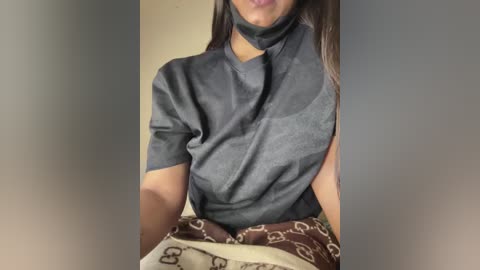 Media: A video of a woman with medium-brown skin, wearing a black, high-neck blouse, partially covered by a brown Hermes scarf, against a plain beige background.