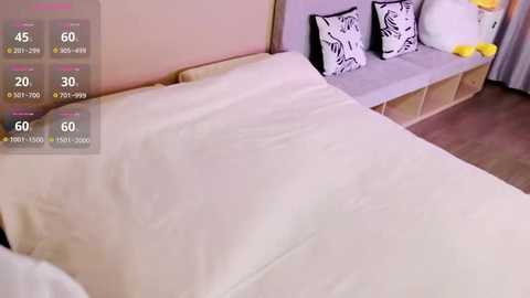 A video of a minimalist bedroom with a beige bedspread, white pillows, and a grey bench with black floral cushions. A digital display shows temperature settings.