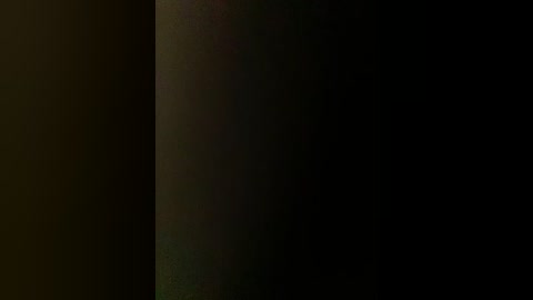 Video of a dimly lit, narrow corridor with a shadowy figure standing in the center, creating a sense of mystery and suspense. The background is mostly black, emphasizing the figure's presence.