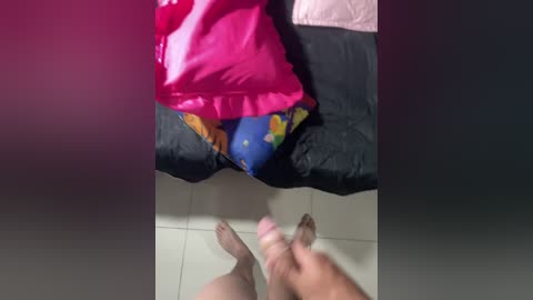 A video showing a woman in a pink satin dress and blue patterned panties, sitting on a bed, with a man's erect penis and testicles in the foreground.
