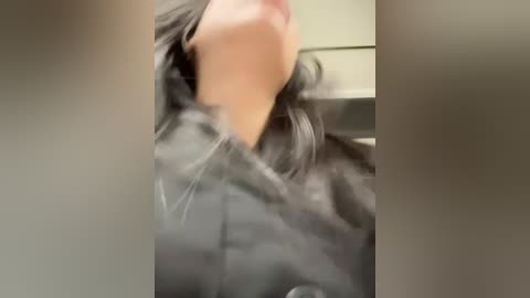 A blurry video of a person with long, black hair, wearing a dark jacket, captured from a low angle, partially obscured by a grayish tint.