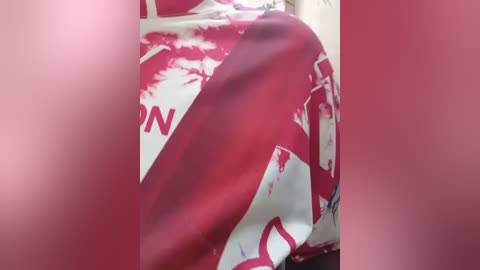 A video of a woman wearing a white shirt with a red abstract design, possibly blood splatter, taken from a low angle, obscuring her face. The background is blurred, and the image has a soft focus.