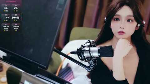 Video of an Asian woman with long brown hair and fair skin, wearing headphones, recording a video on a computer screen with a microphone.