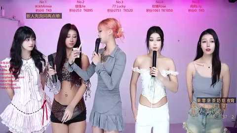 Video of four Asian women, diverse in appearance and attire, holding microphones, standing in a studio with pink and white backdrop.