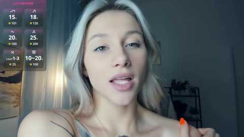 Video of a young, fair-skinned woman with platinum blonde hair, wearing a sleeveless top, with a digital overlay showing weather statistics.