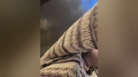 A video of a woman's lower torso in a cozy, patterned sweater, taken from a low angle, showing the texture and warmth of the knit fabric.