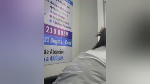 A video of a hospital room with a bed, a patient lying down, and a poster with medical information in Spanish.