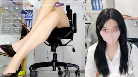 Video of an East Asian woman in a lab coat, seated at a desk, wearing a face mask, with a virtual overlay of a female model's legs crossed, in a clinical setting.