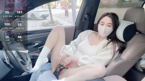 A video of an Asian woman in a white robe, mask, and leopard-print panties, sitting in a car, with a digital screen showing 38% COVID-19 risk.