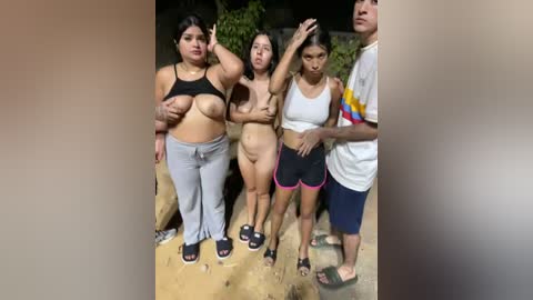 Video of five young women, topless, standing outdoors; two covering breasts with hands, others bare-chested, wearing sportswear.