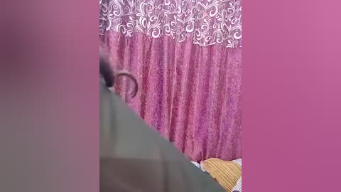 A video of a woman in a purple dress with white floral patterns, partially obscured by a pink overlay.