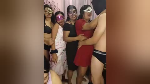 Media: Video of a group of five women and a shirtless man in a dimly lit room, wearing masks, one in a red dress, others in black lingerie, embracing, background with curtains.