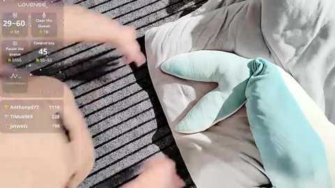 Video of a person wearing blue gloves and beige pants sitting on a striped black and grey cushion, with a digital screen showing medical vitals.