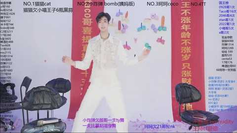 A video of a Chinese magician performing a card trick on stage, surrounded by Chinese text and colorful banners. The background is white, and the magician wears a white suit and tie.