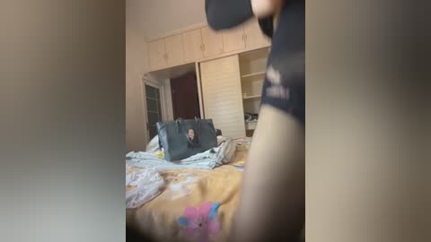 Video of a messy bedroom with a beige bedspread, open closet doors, and a laptop on the bed. The image has a blurry, out-of-focus effect.