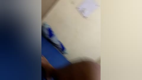 A blurred video shows a hand holding a brush, painting a white wall with blue accents. The image is slightly out of focus, making it difficult to discern specific details.