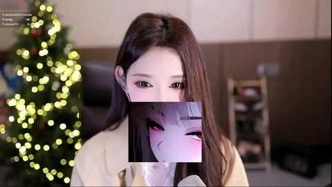 A video of a young woman with long brown hair, wearing a beige sweater, partially obscured by a video game character's head, in a cozy room with a Christmas tree and warm lighting.