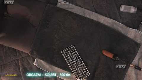 A video of a dark grey, textured table with a white, square-shaped device, a small screwdriver, and a \"LOVENCE\" logo, set against a dark, patterned background.