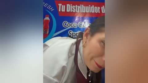A video shows a woman with dark hair, wearing a white lab coat, and a maroon shirt. The background features a blue and red promotional poster for \"Tu Distribuidor Rojo.\