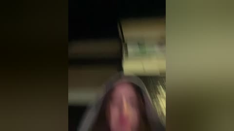 A blurry video of a woman's face, showing only her nose and mouth, with a blurred background featuring indistinct objects.