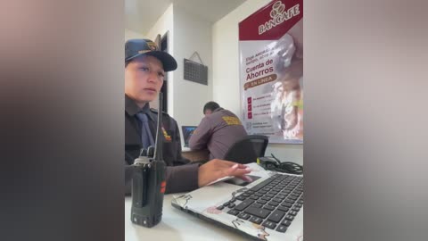 Video of a serious-looking bank employee in a dark uniform, sitting at a desk with a laptop, behind a large \"Banco Galicia\" poster and another employee.